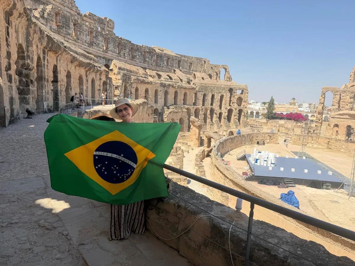 Anete no Coliseu de El Jem segurando a bandeira do Brasil